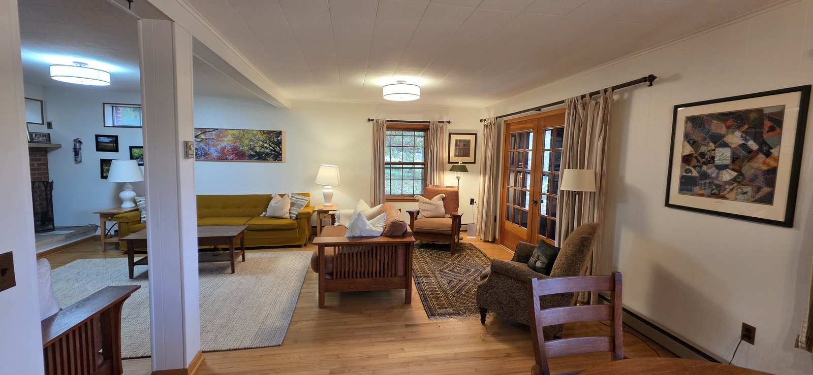 Open living room with comfortable seating, a wood-burning fireplace, and French doors to the deck